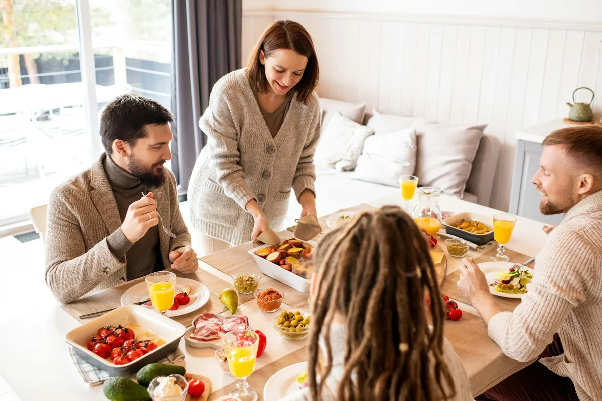 Smiling friends enjoy a delicious indoor brunch with fresh fruit and conversation around a table.