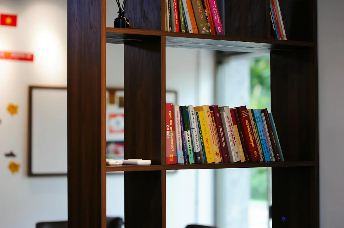 A bookshelf filled with colorful Vietnamese books in a modern Hanoi office space with natural light.